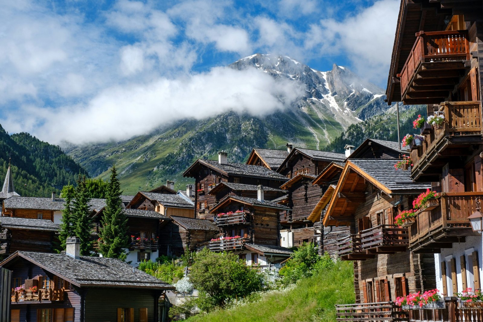 Switzerland is one of the safest countries in the world for solo travel. Featured is a picture of a town under Switzerland's beautiful mountains.